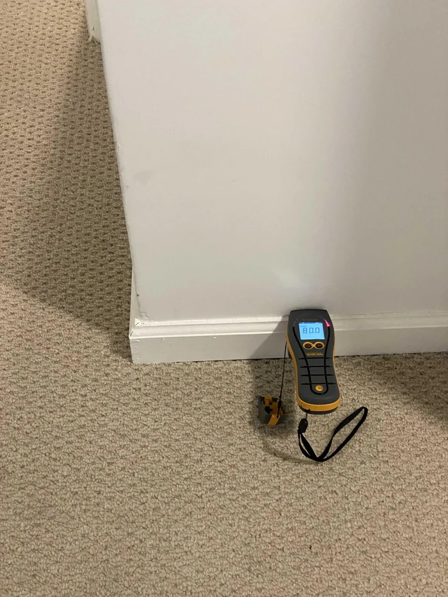 A moisture meter at the base of a wall during a Glenside water-damage assessment.